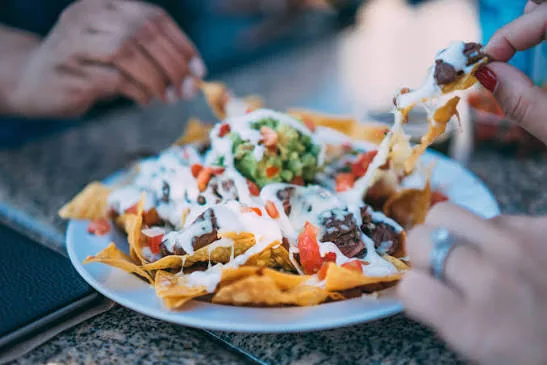 Varias personas comparten un plato de comida en una mesa