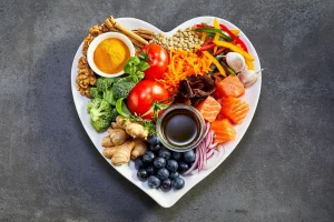 Plato en forma de corazón con verduras, fruta, huevo, pescado y frutos secos